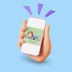 Una mano sosteniendo un teléfono móvil que muestra una imagen de un niño acostado "tummy time", sobre un fondo azul.